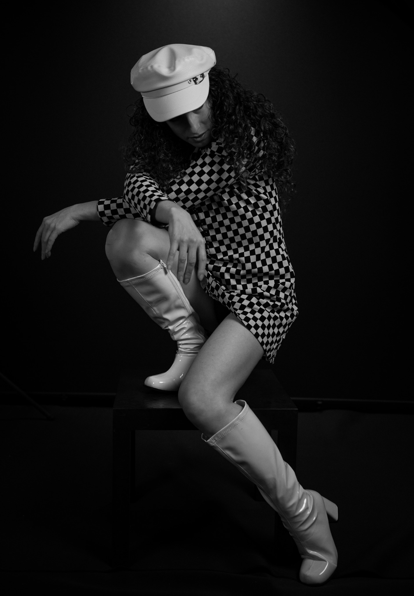 Black-and-white mod fashion portrait in a checkerboard dress and white boots