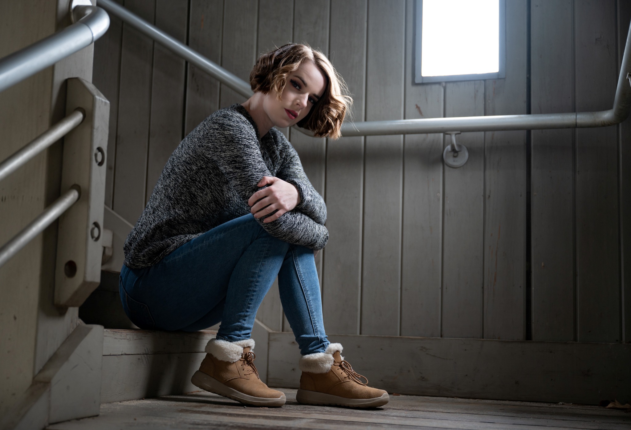 Casual environmental portrait of a woman seated in a wooden shelter